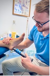 Scott performing shockwave therapy ona persons foot